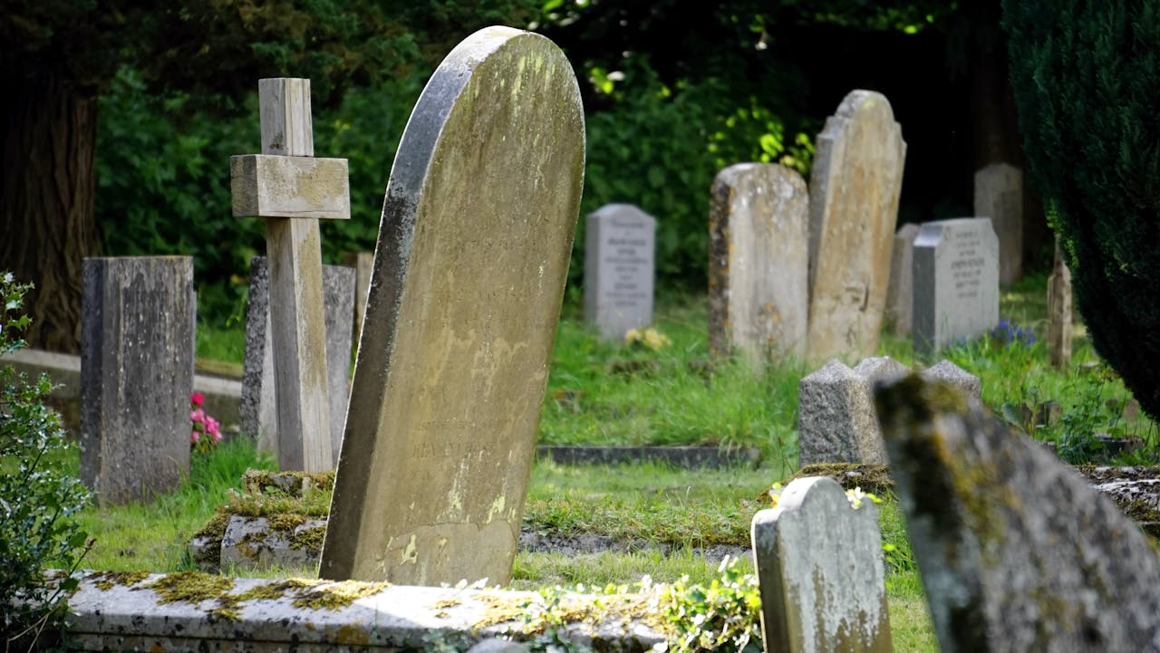 Weathered tombstones in a tranquil cemetery surrounded by greenery.